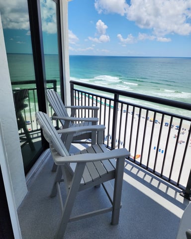 Oceanfront balcony with gray Adirondack chairs overlooking sandy beach and turquoise waves