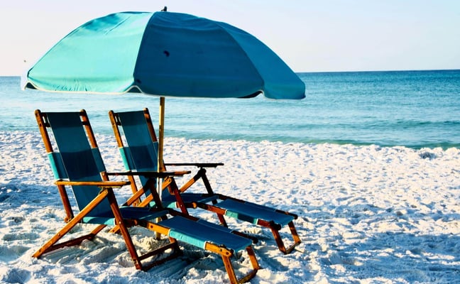 Beach chairs and turquoise umbrella on white sand at the Gulf